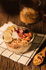Bowl of yogurt with berries  granola and banana on wooden table. Healthy food, vegeterian, dieting and weight loss concept.