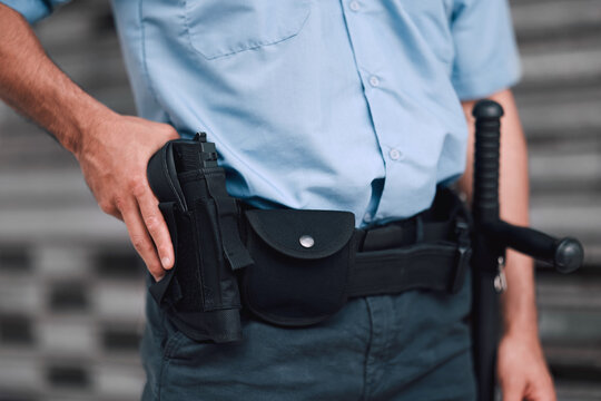 Hand, gun and security with an officer on duty or patrol in the city for safety and law enforcement. Police, service and armed response with a guard outdoor in an urban town for crime prevention