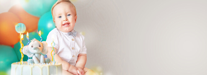 Banner of little boy (1-year-old) with delicious birthday cake (sweets with candles of number one, decoration).  Celebrating child's first year birthday. Copy space. Empty space for your message.