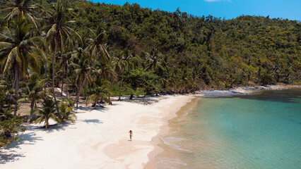 Podróżnik idący po pięknej plaży, rajska wyspa z palmami i turkusowa woda. - obrazy, fototapety, plakaty