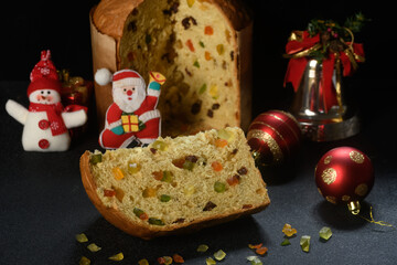 slice of panettone on a black wooden table and Christmas decorations