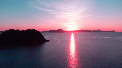 Piękny zachód słońca, kolorystyka różowo pomarańczowa, tropikalne wyspy i ocean.