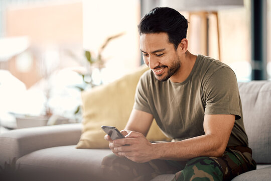Happy, man and texting on cellphone in living room for online mobile app, scroll social media and notification on sofa. Asian male person typing on smartphone, contact and internet download at home