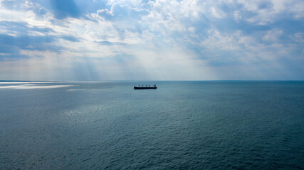 Self-unloading bulk carrier at Rio De La Plata anchorage. Sun rays shining through clouds.  Aerial wide view.