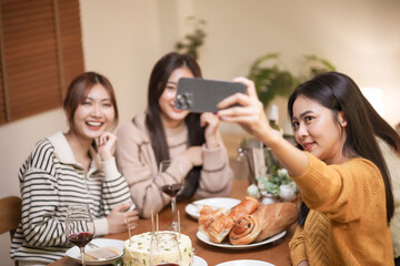 Asian sister friends making selfie and smiling with smartphone. celebrating with Birthday cake.