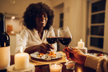 Focus on a wine glasses while clinking during a toast on a romantic dinner at home