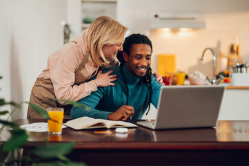An interracial remote worker at home with his wife.