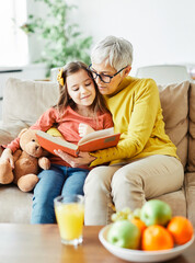 grandchild family child grandparent grandmother book reading elderly granddaughter girl  happy...