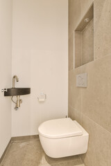 Naklejka na ściany i meble a white toilet in a bathroom with beige tiles on the floor and wall behind it is a shelf for storage