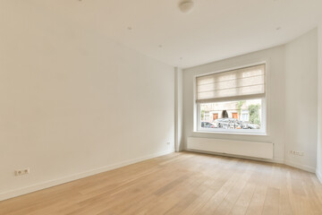 Fototapeta premium an empty room with white walls and wood flooring on the right side, there is a window in the corner