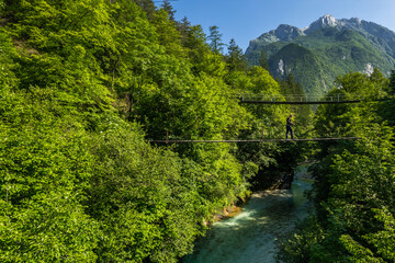 Active young man walking over suspension bridge in mountains