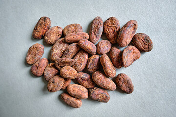 Close-up image of a pile of dry cocoa beans (seeds of the cacao tree) on a rough paper. Perfectly organic healthy superfood ready for consumption or processing into powder, butter, and chocolate. 