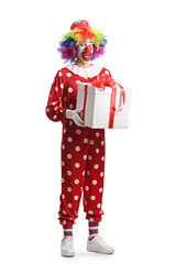 Full length portrait of a clown in a red costume holding a present box