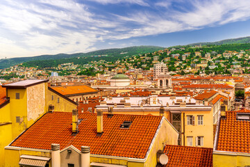 panoramic landscape view of green summer city with yellow houses, green forest and mountains above...