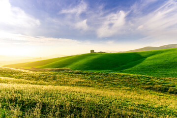 scenery rural view of a contryside farm in green fields and hills with amazing cloudy sky on background