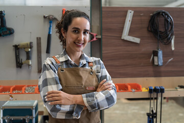 Portrait of young woman carpenter working at carpentry workshop. Happy smiling joiner female...