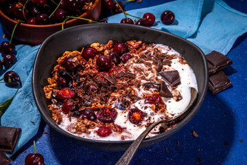Chocolate and cherry oatmeal. Sweet breakfast bowl with cherry, chocolate drops and sauce, oatmeal and vanilla yogurt or melting ice cream