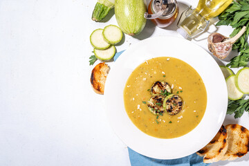 Squash vegetable marrow cream soup, white zucchini pureed soup with grilled marrow or zucchini slices, cheese and greens, white concrete table background copy space