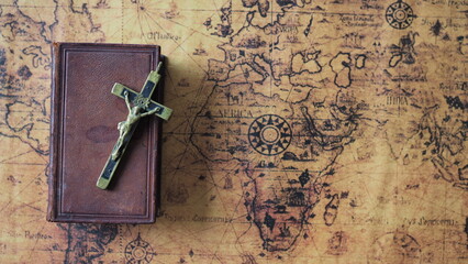 bible and cross placed on vintage world map