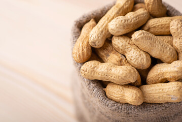 Bag with peanuts on wooden background. Close up of unpeeled peanuts, harvest of nuts