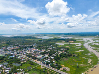 Fototapeta premium Aerial view of National Route 20 in Dong Nai province, group of floating house on La Nga river, Vietnam with hilly landscape and sparse population around the roads.