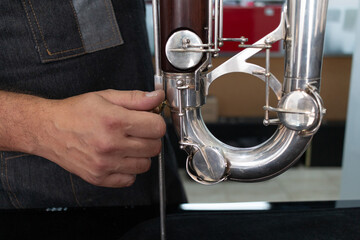 Naklejka premium specialist technician adjusting the base of a contrabass clarinet