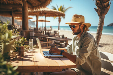 A guy on the beach working with a computer