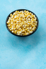 Bowl with corn seeds isolated on blue colour background