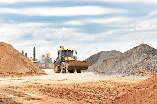 Powerful wheel loader or bulldozer at the construction site. Loader transports sand in a storage bucket. Powerful modern equipment for earthworks and bulk handling.
