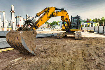 A powerful crawler excavator is working on a construction site. Close-up. Preparation of a pit for...
