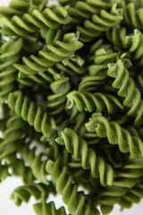 Raw green fusilli pasta, natural based on spinach and spirulina. Delicious and healthy food. Close-up.
