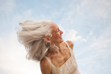Happy senior woman portrait  with her hair dancing in the wind.  - 620264116