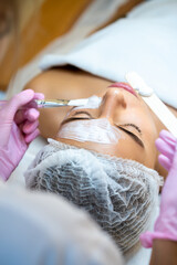 Fototapeta premium Cosmetologist applying mask to woman face in spa beauty salon.