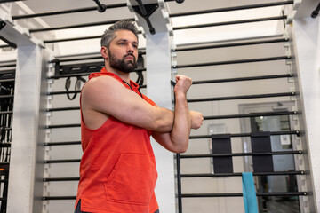 Athletic man warming up and stretching arms before training fitness gym, body care.