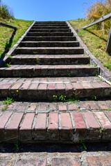 Weathered brick stairs leading up to a blue summer sky
