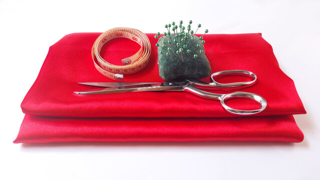 Scissors, pincushion and tape measure on red fabric

