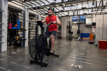 Adult athletic man doing cycling on exercise bikes at the gym.
