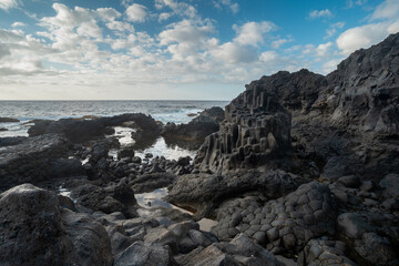Long exposure. rocky beach with a natural arch with blue sky. Charco Azul. El Hierro island. Canary Islands	
