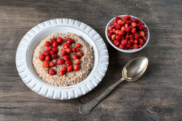 Spelled porridge for breakfast. Wheat porridge with strawberries. Seasonal summer wild berry. Healthy food.