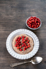 Spelled porridge for breakfast. Wheat porridge with strawberries. Seasonal summer wild berry. Healthy food.