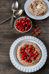 Spelled porridge for breakfast. Wheat porridge with strawberries. Seasonal summer wild berry. Healthy food.