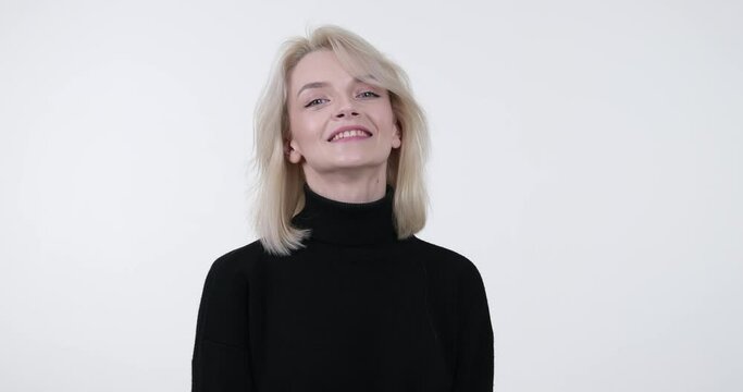 Caucasian woman stands against a white background. With a warm smile on face, she confidently performs the Call Me gesture, indicating a desire to receive a phone call.