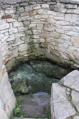 A stone wall with a water hole
