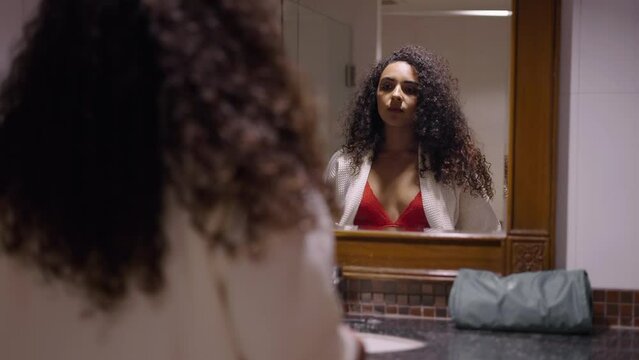 Latina girl in front of a mirror takes off a shirt and stays in lingerie
