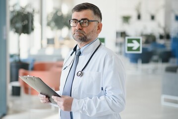 Portrait of serious senior doctor in eyeglasses and in white coat.