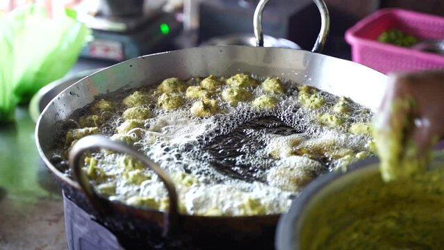 This is closeup shot of Frying Fritters by hand manually in Indian street food during monsoon.