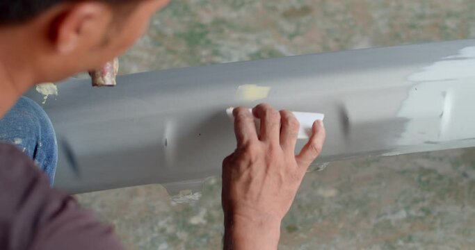 Repair car front bumper by puttying close up work after the accident by working sanding primer before painting.Using plastic putty yellow apply over the missing parts of the plastic.