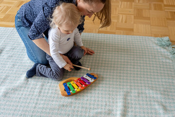Mother and little child playing with toys, xylophone