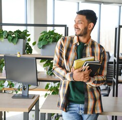 Happy smart indian or arabian guy, mixed race male, university student, stands in the library...