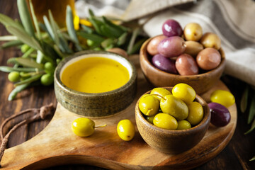 Freshly picked olives berries in wooden bowls and pressed oil served on old wooden boards.
